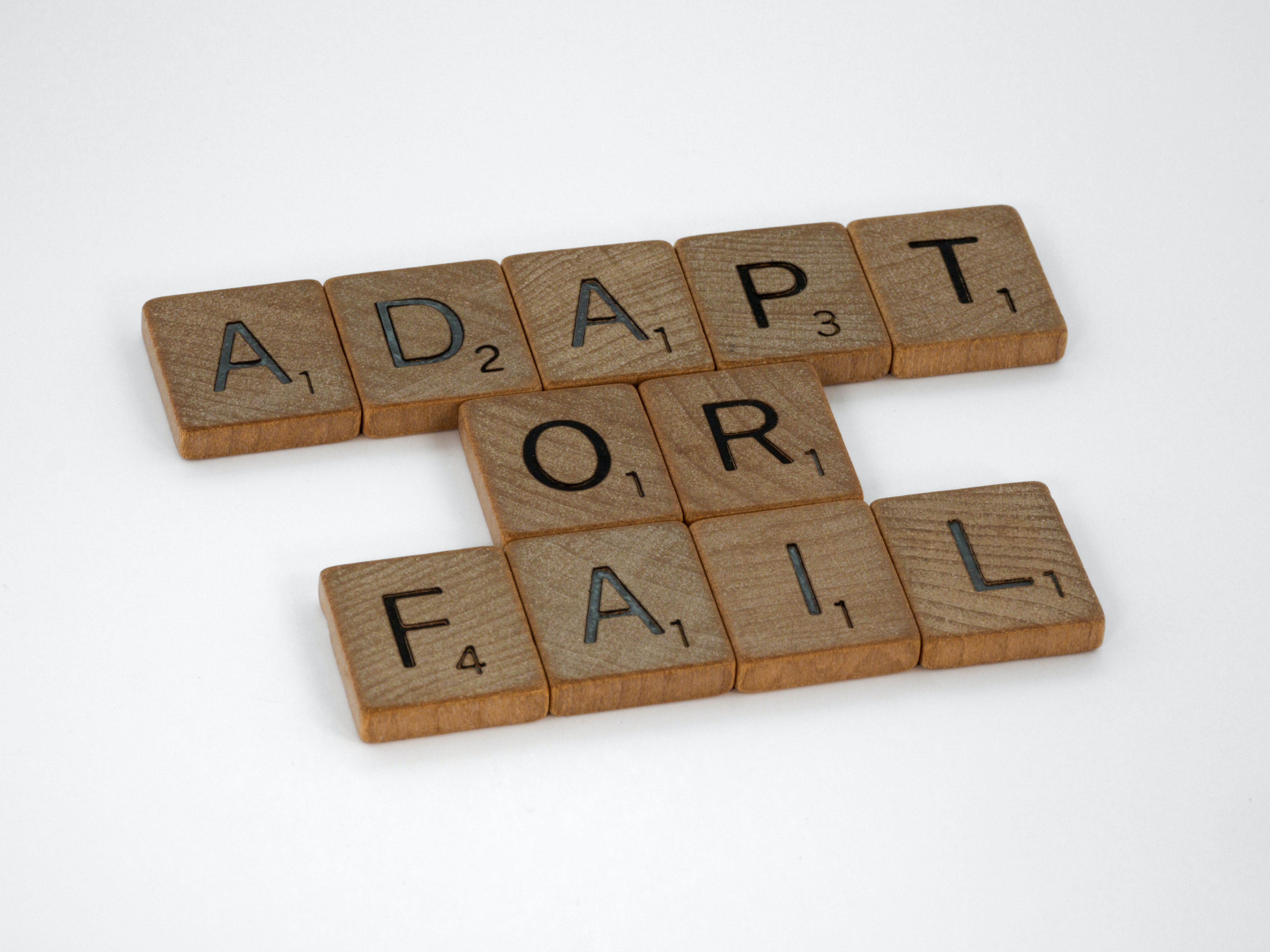 Wooden Scrabble tiles that read 'adapt or fail'